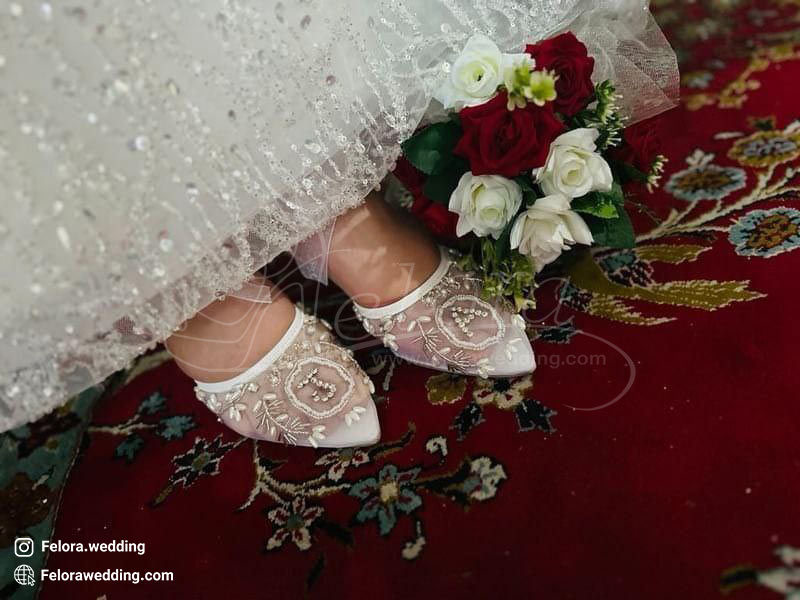 تصویر کفش عروس توری تزیین شده بر روی فرش